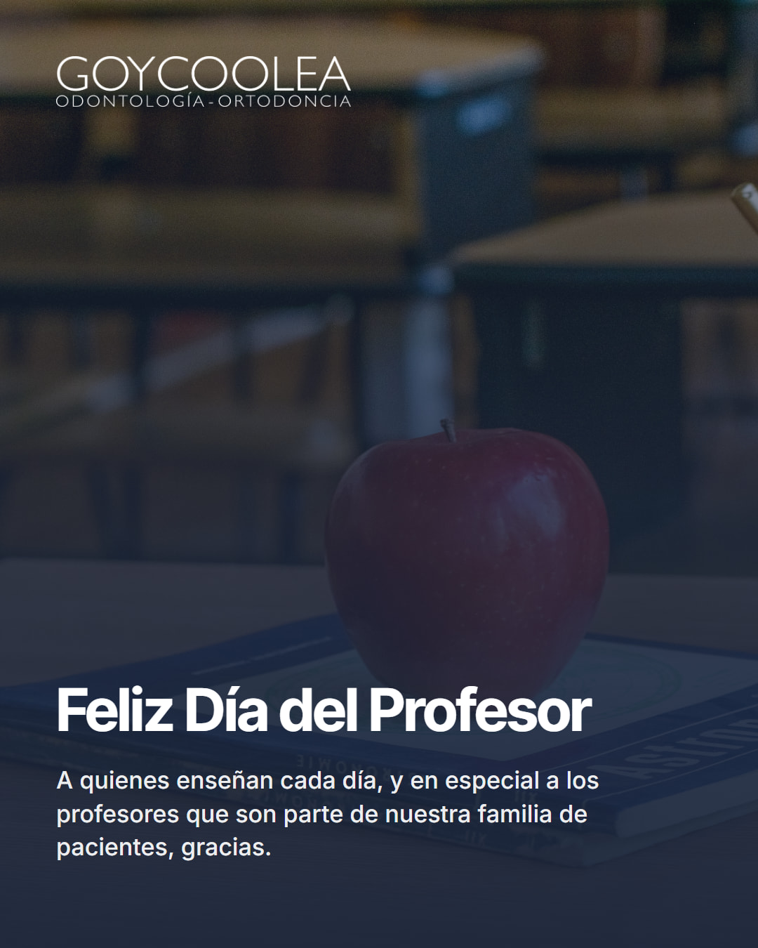 Saludo por el Día del Profesor con foto de una manzana sobre libros en un escritorio de sala de clases